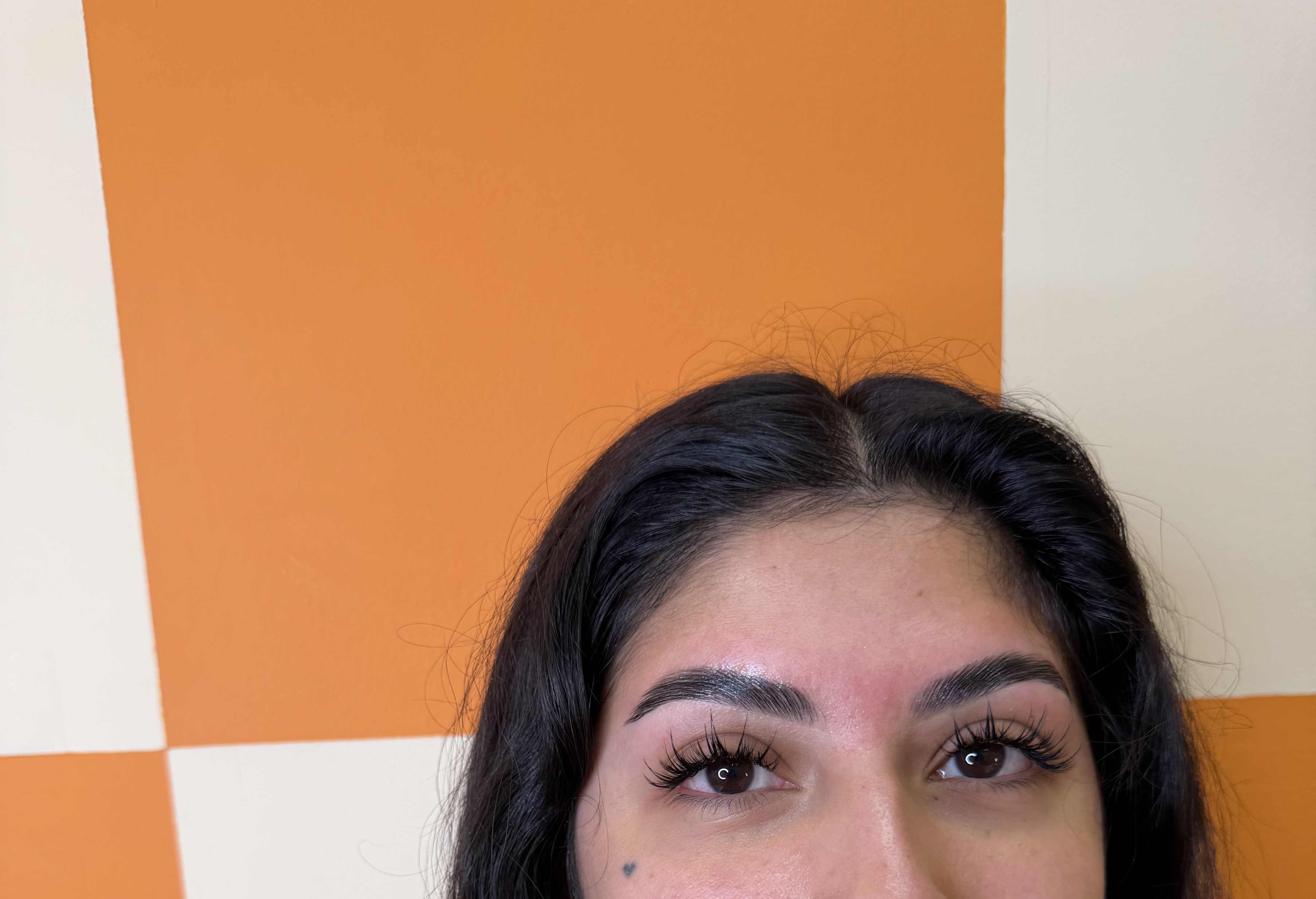 Client showing brows and lashes against checkered wall