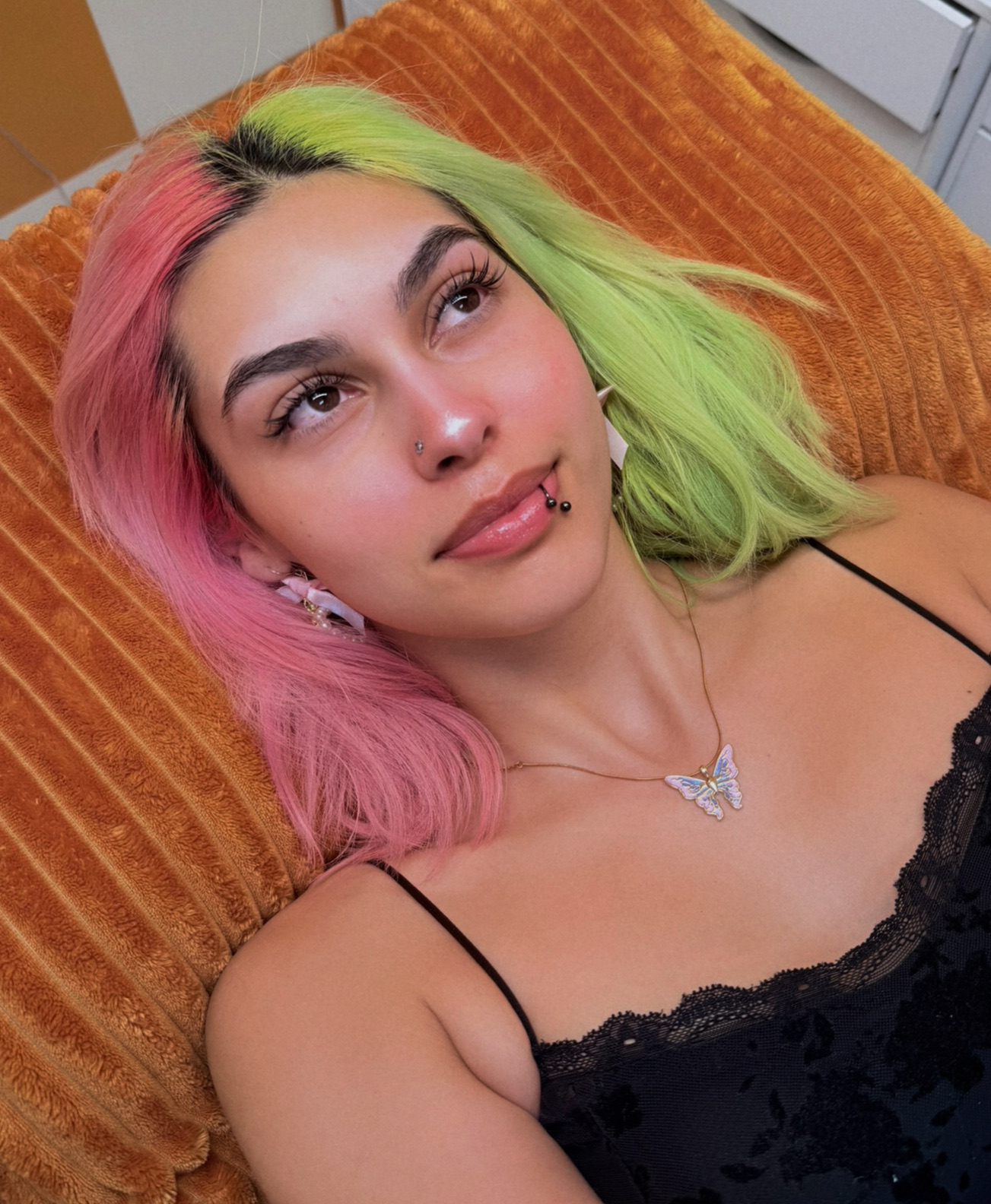 Happy client with pink and green hair on orange pillow
